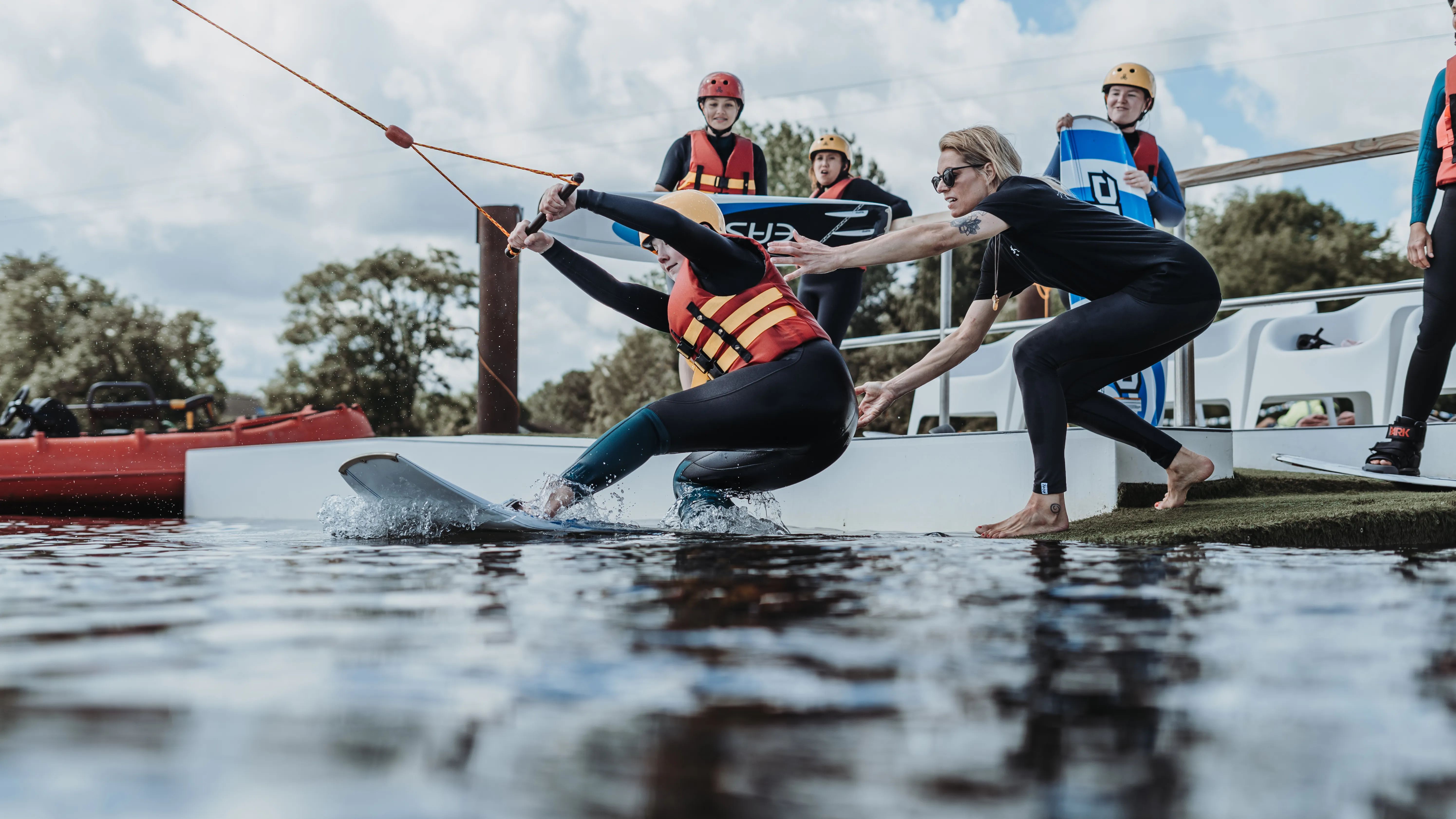 Trainerin unterstützt eine Einsteigerin beim Wakeboardstart bei Supieria